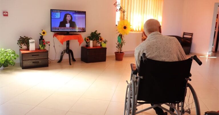 Persoană vârstnică în fotoliu rulant, într-un cămin de bătrâni